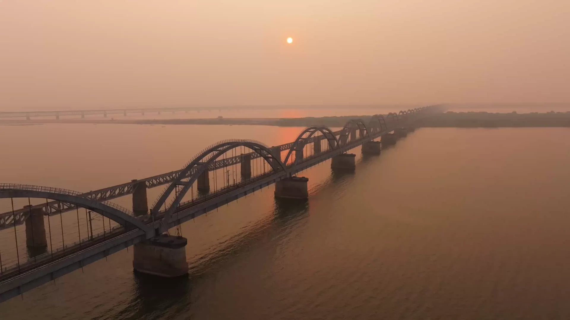 The Godavari arch bridge at Rajamahendravaram crossing the river under a low sun, seen from the air