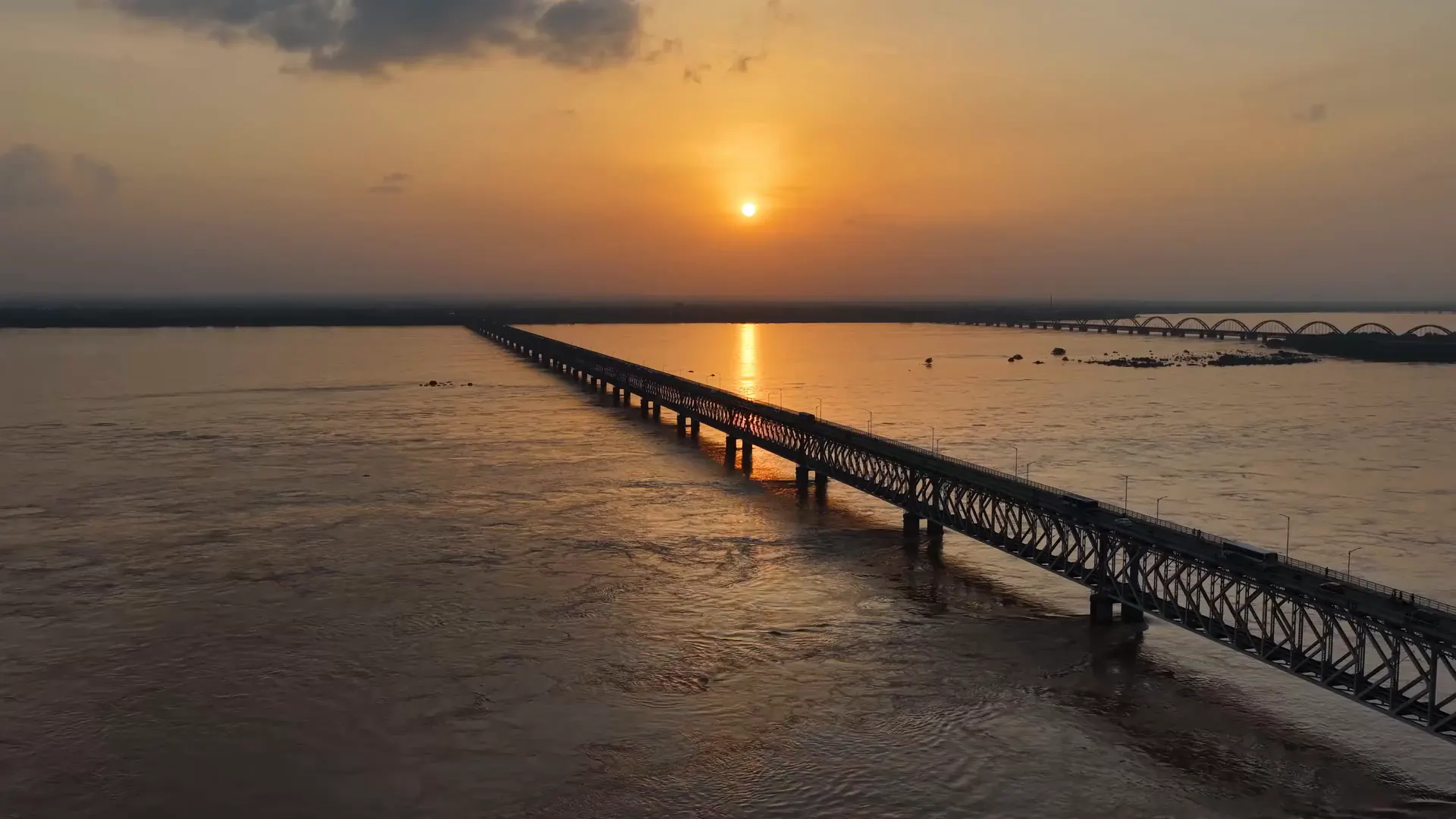 A long rail bridge running out across the Godavari at sunset, seen from the air near Rajamahendravaram