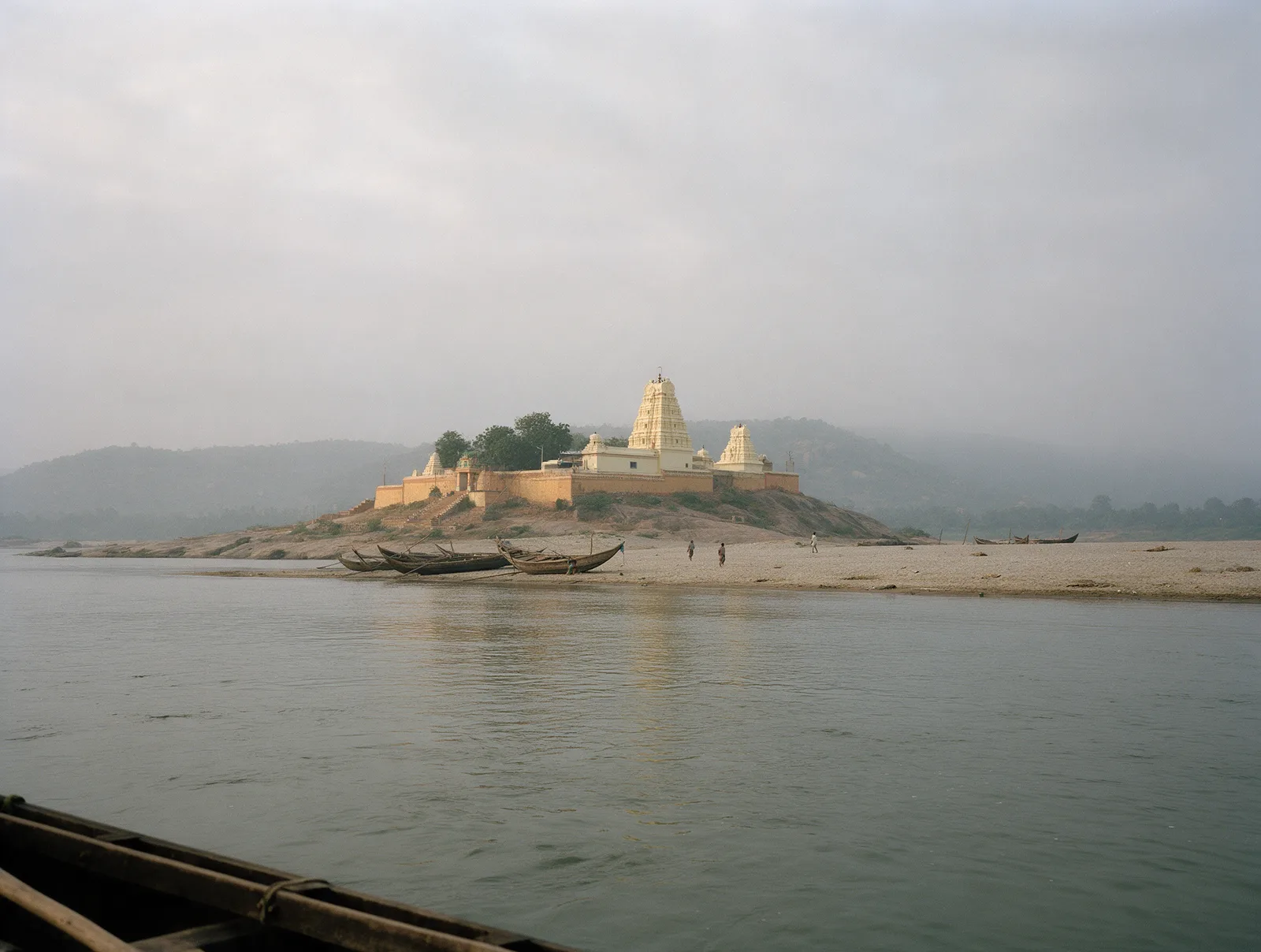 From a country boat on a hazy morning, the cream-painted Veerabhadra temple sits small on its sandy island across the grey-green Godavari at Pattiseema, wooden boats pulled up on the sand