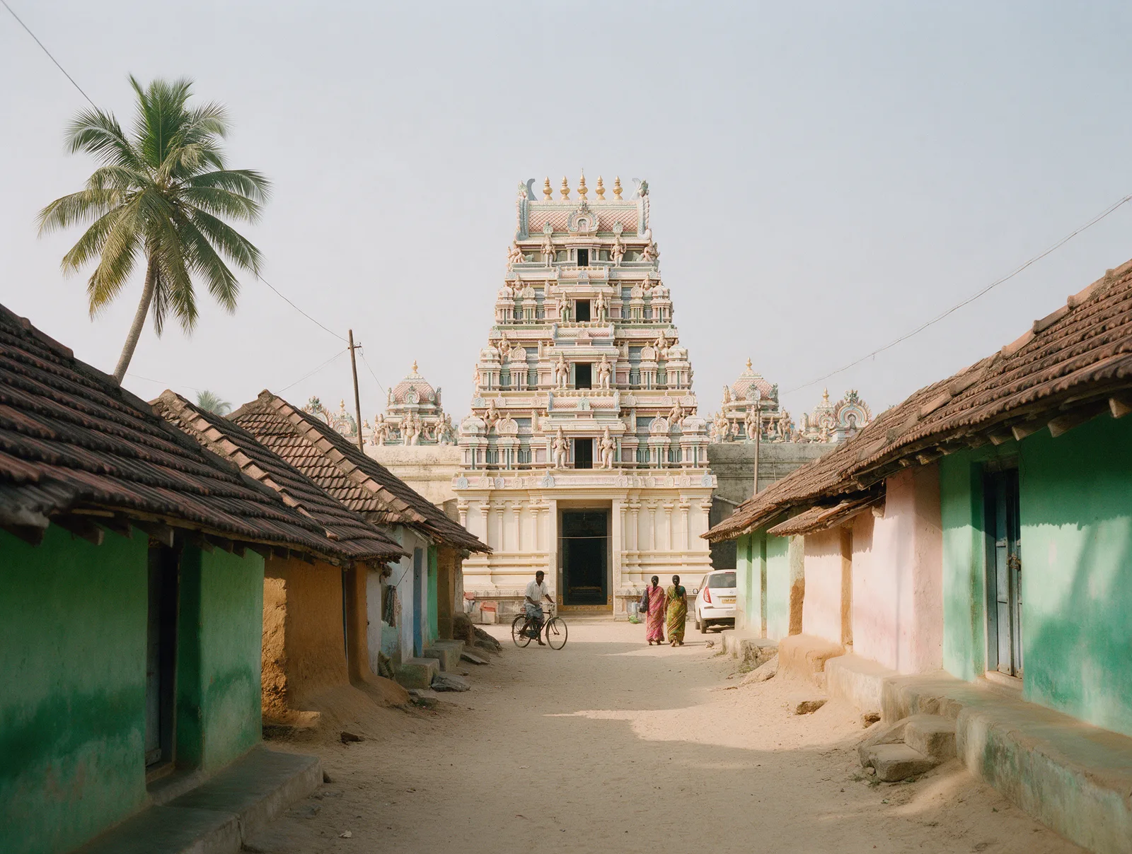 The pastel-painted gopuram of the Jaganmohini Kesava temple at the end of a tiled-roof village lane in Ryali