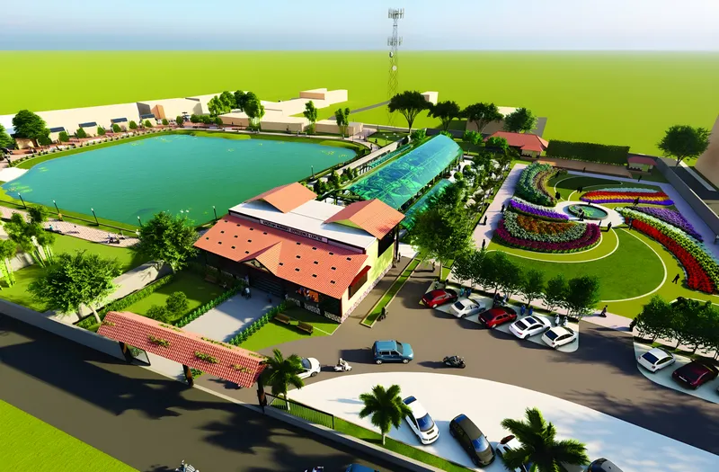 Aerial view of the Kadiyam Experience Centre: a lake, a red-roofed hall, a glasshouse and flower beds beside the road