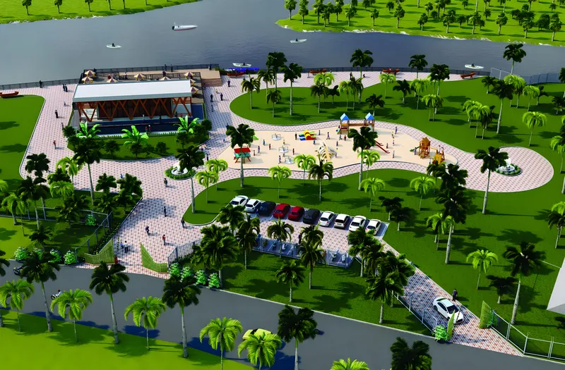 Aerial view of a wayside amenity on the Nidadavolu canal: palm-lined lawns, a playground, parking and a canal-side hall