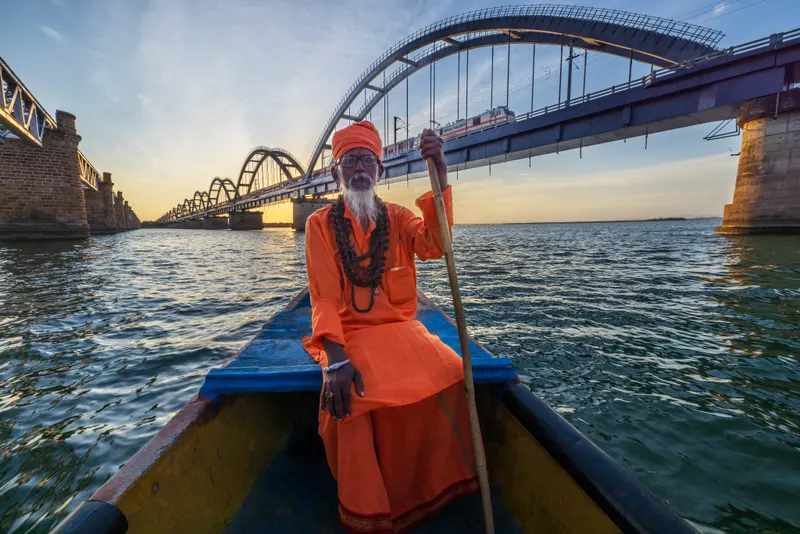 A sadhu on a small boat in the wide open river